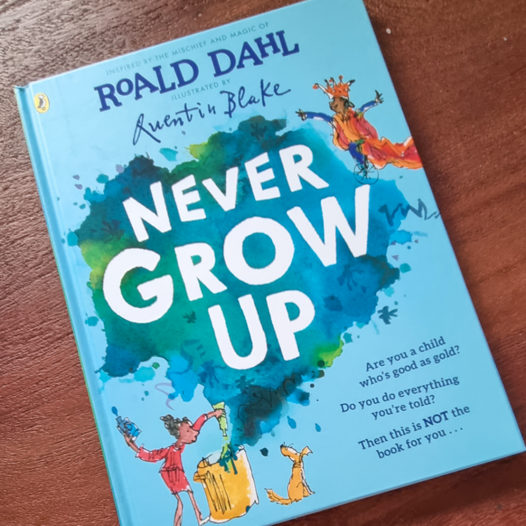 book on table - book has blue cover and is called Never Grow Up
