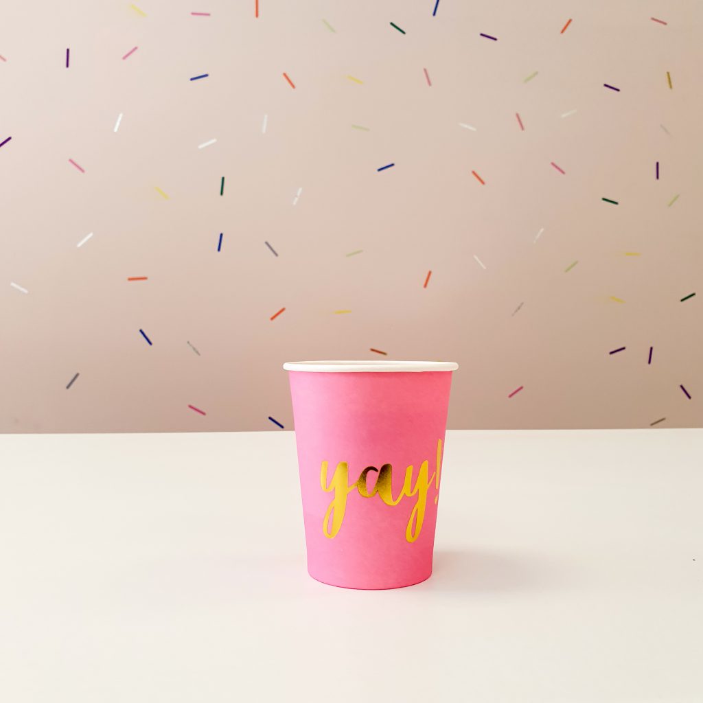 pink cup yay with sprinkles on a background wall