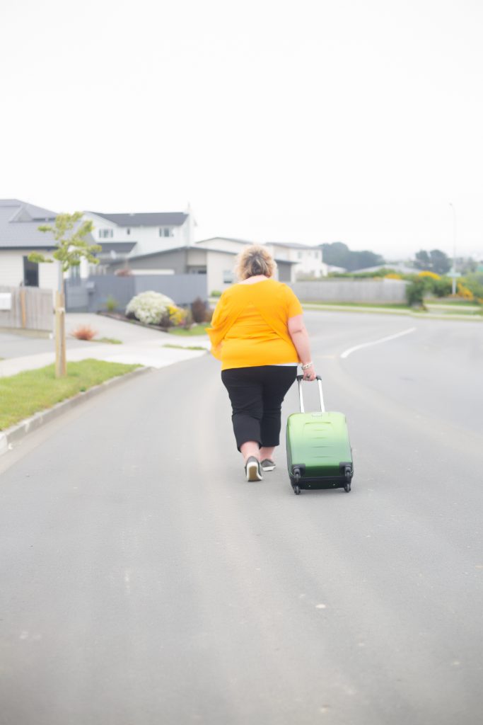 woman walking down road with a suitcase