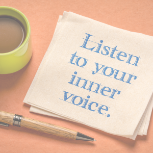 serviette with the words listen to your inner voice written on it. A pen and cup of coffee is also on the table.