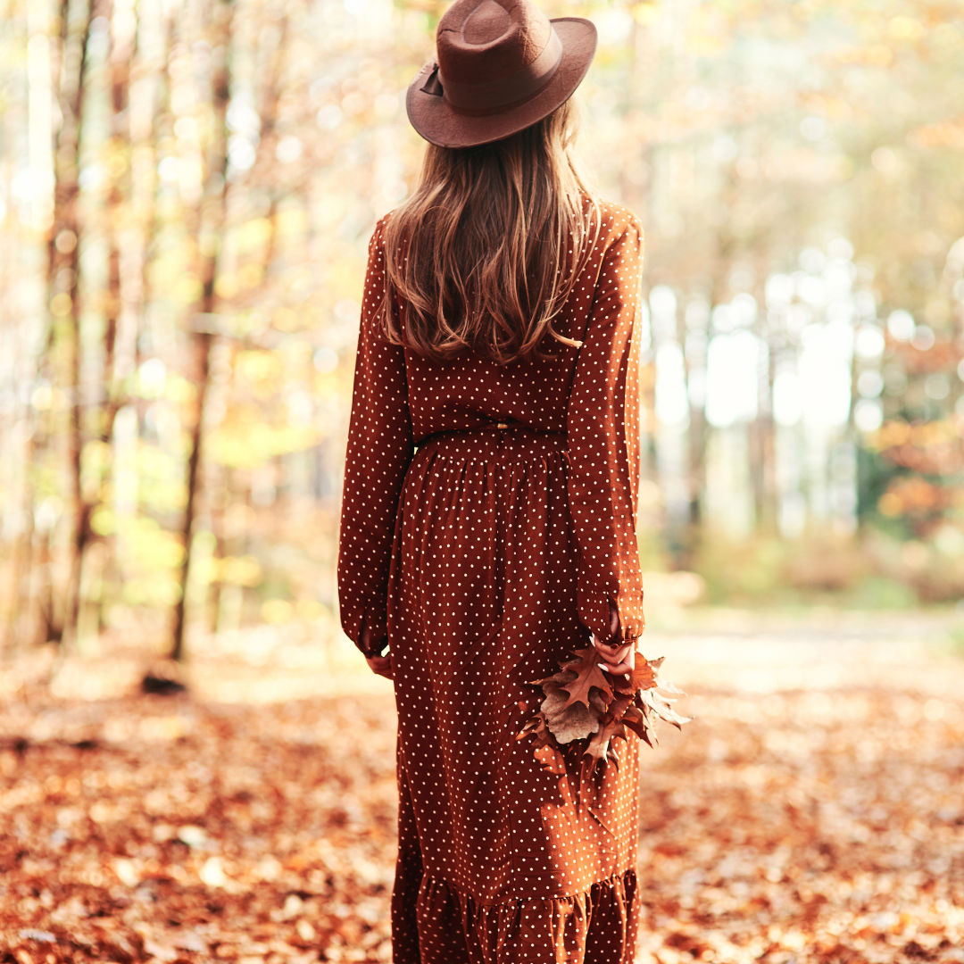 Picture of a woman walking in nature, embracing the beauty of autumn and taking time to reconnect with herself.